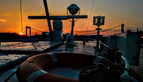 Man sitting in boat against sky during sunset