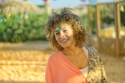 Portrait of smiling woman with painted forehead in sunny day