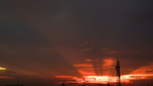 Low angle view of silhouette electricity pylon against sky at sunset