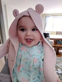 Close-up of cheerful baby girl wearing warm clothing at home