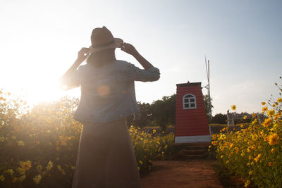 Rear view of woman standing against sky during sunset