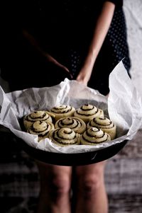 Midsection of woman holding tarts in baking pan