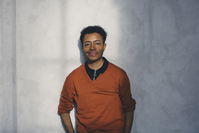 Portrait of young man standing against wall