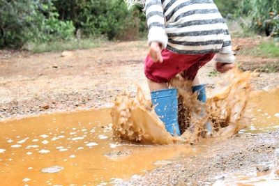 Low section of boy jumping in puddle