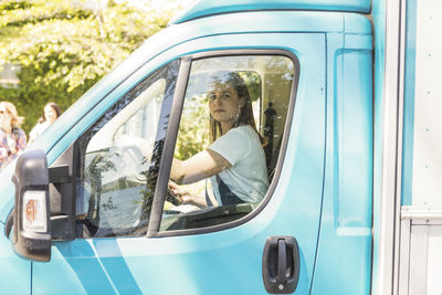 Side view portrait of confident young female owner driving food truck