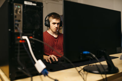 Young man playing video games with computer at desk