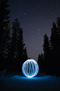 Illuminated light painting on snow covered field against sky at night