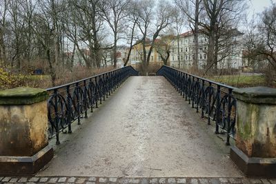 Footbridge amidst trees against sky
