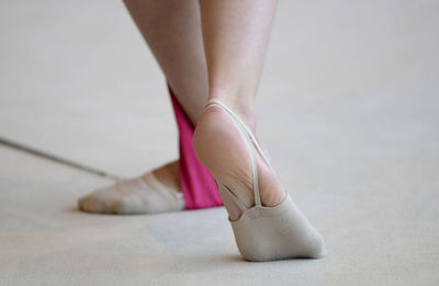 Low section of woman wearing ballet shoes on floor