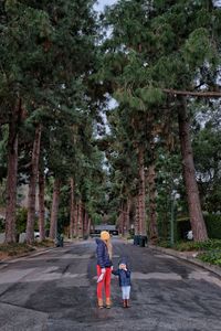 Rear view of people walking by trees