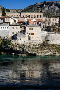 Houses by river in city against sky
