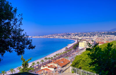 High angle view of townscape by sea against blue sky