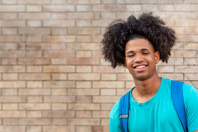 Portrait of smiling young man against brick wall