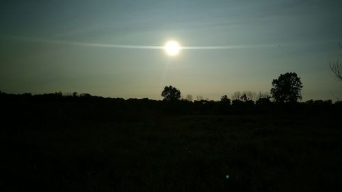 Silhouette trees on field against sky