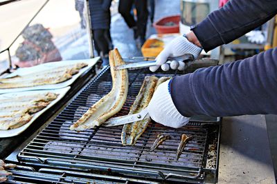 Midsection of person preparing food on barbecue grill