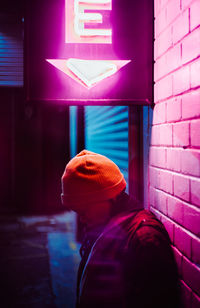 Side view of woman standing by wall at night