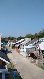 Houses by buildings against clear blue sky