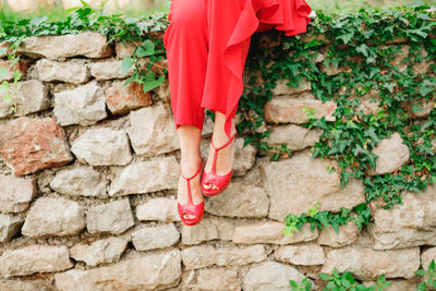 Low section of woman standing on stone wall