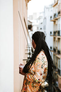 Rear view of woman standing against wall