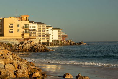 Buildings by sea against clear sky