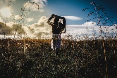 Rear view of man standing on field against sky