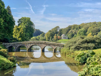 Arch bridge over river against sky