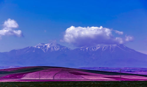 Scenic view of field and mountains against blue sky