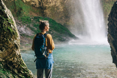 Rear view of woman standing against waterfall