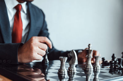 Midsection of businessman playing chess at office