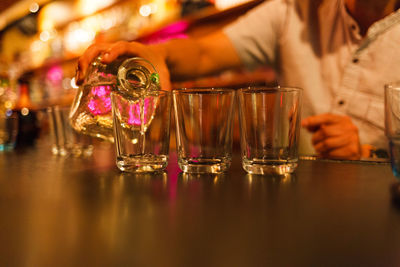 Bartender pouring tequila in glass on table