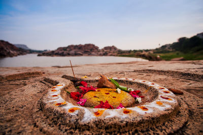 Close-up of fruits on sand at beach against sky