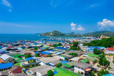 High angle view of townscape by sea against blue sky