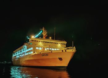 Illuminated ship moored in sea against sky at night