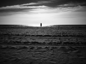 Rear view of silhouette man on beach against sky