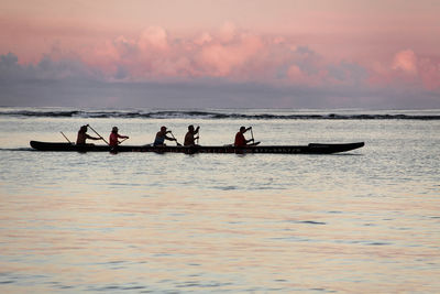 Silhouette people on sea against sky during sunset