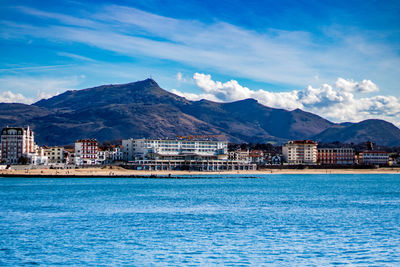 Scenic view of sea and houses against blue sky