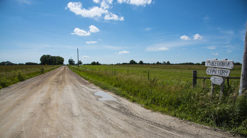 Road amidst field against sky