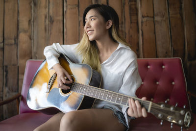 Smiling young woman playing guitar