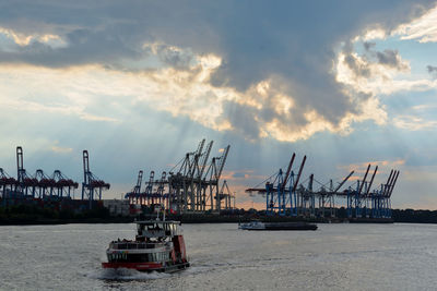 Cranes at commercial dock against sky