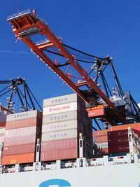 Low angle view of crane against clear blue sky