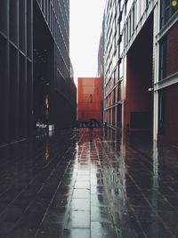 Wet street amidst buildings in city during rainy season