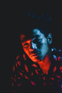 Close-up portrait of young man against black background