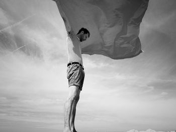 Low section of man with umbrella against sky
