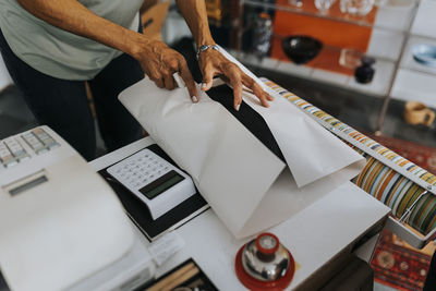 Midsection of saleswoman wrapping product at checkout in antique shop