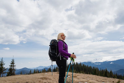 Rear view of man standing on mountain against sky