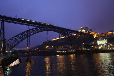 Illuminated bridge over river against sky at night