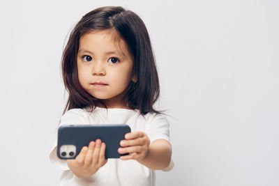 Portrait of young woman using mobile phone against white background