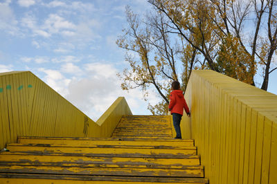 Low angle view of boy on staircase against sky