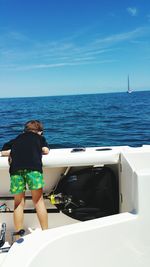 Rear view of woman standing on boat against sea