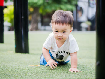 Baby boy playing on grass amidst torii gates at park